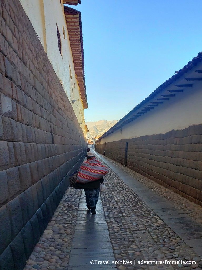 Woman walks through narrow cobblestone alley