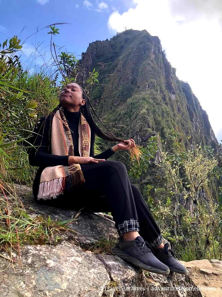 Girl with scarf on sits with mountain in background