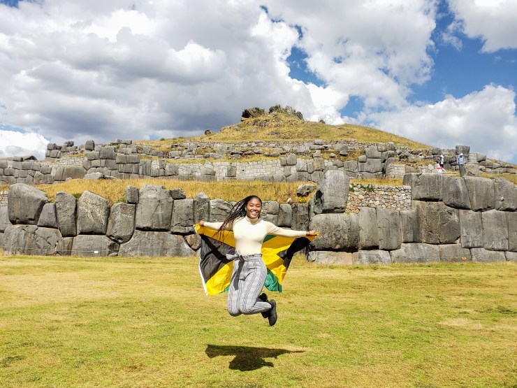Girl jumping with Jamaican flag at Sacsayhuaman
