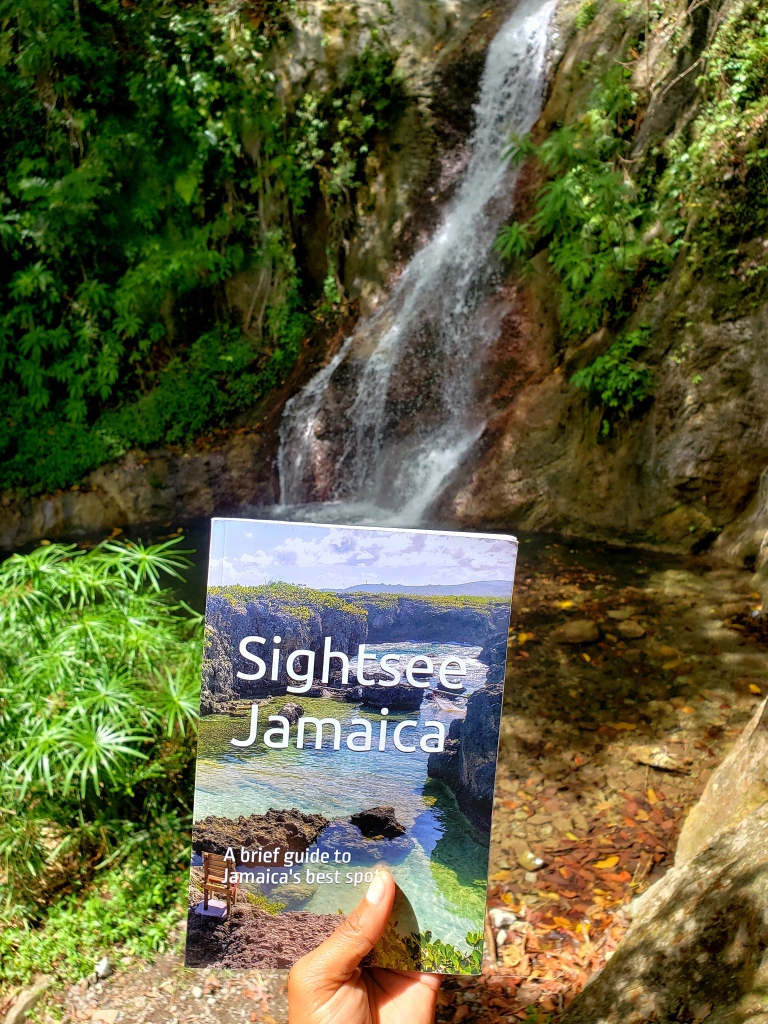 Jamaican travel guidebook in front of waterfall