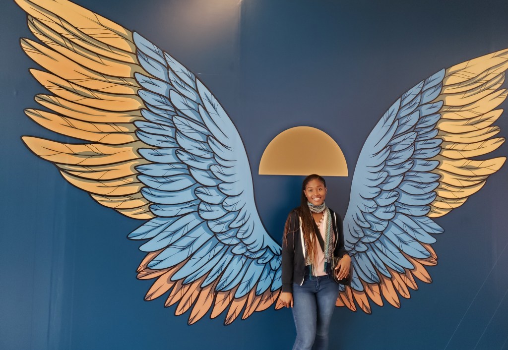 Girl standing in front of mural with butterfly wings