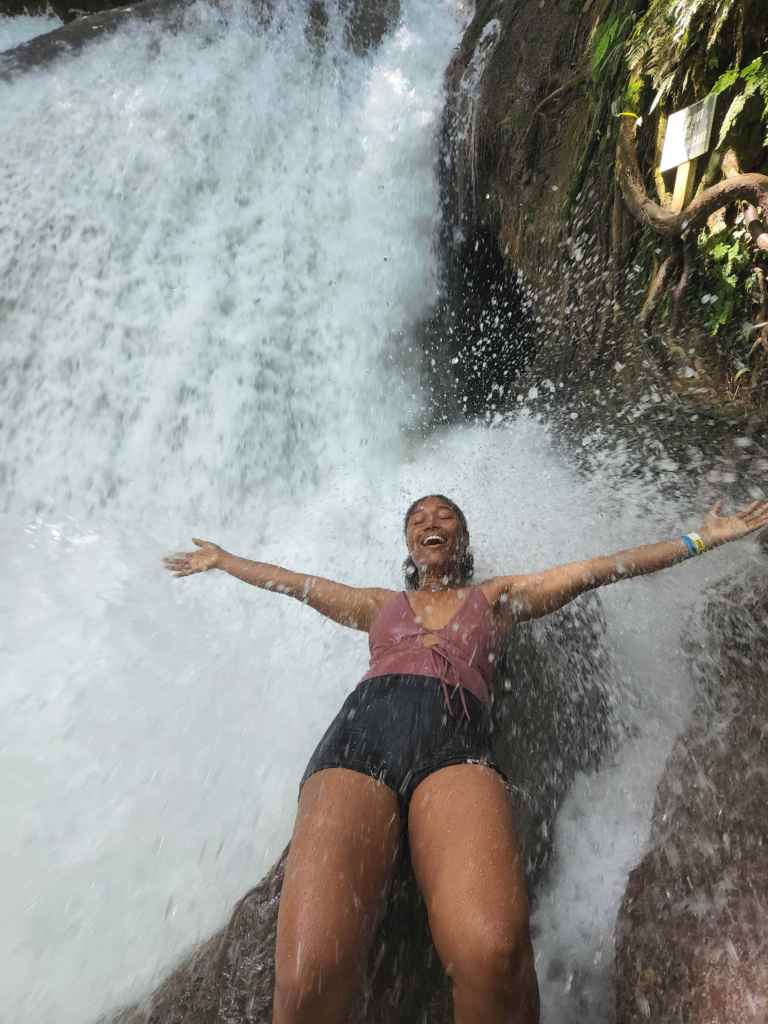 Girl lying on rock next to waterfall